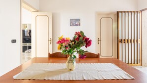 A dining table with a white tablecloth, a vase with flowers, and wooden chairs.