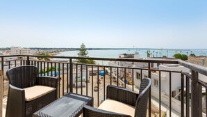 A balcony with wicker furniture overlooking a coastal cityscape. - 3535 Appartamento Antares by Barbarhouse (Porto Cesareo)