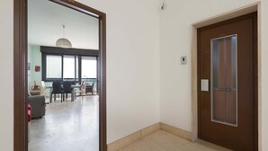 A hallway with a wooden door and a glass door leading to a dining area with a table and chairs. - 3535 Appartamento Antares by Barbarhouse (Porto Cesareo)