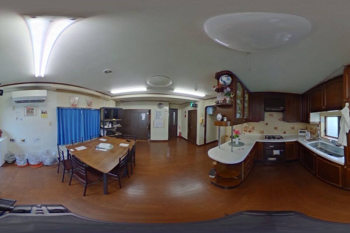 A spacious kitchen with wooden cabinets, a dining area with a wooden table, and a small refrigerator.
