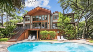 Una casa de dos pisos con piscina, un balcón y una escalera que lleva al piso superior.