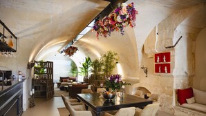 Un comedor amplio con un techo alto en arco, una mesa central con sillas y un arreglo floral colgante.