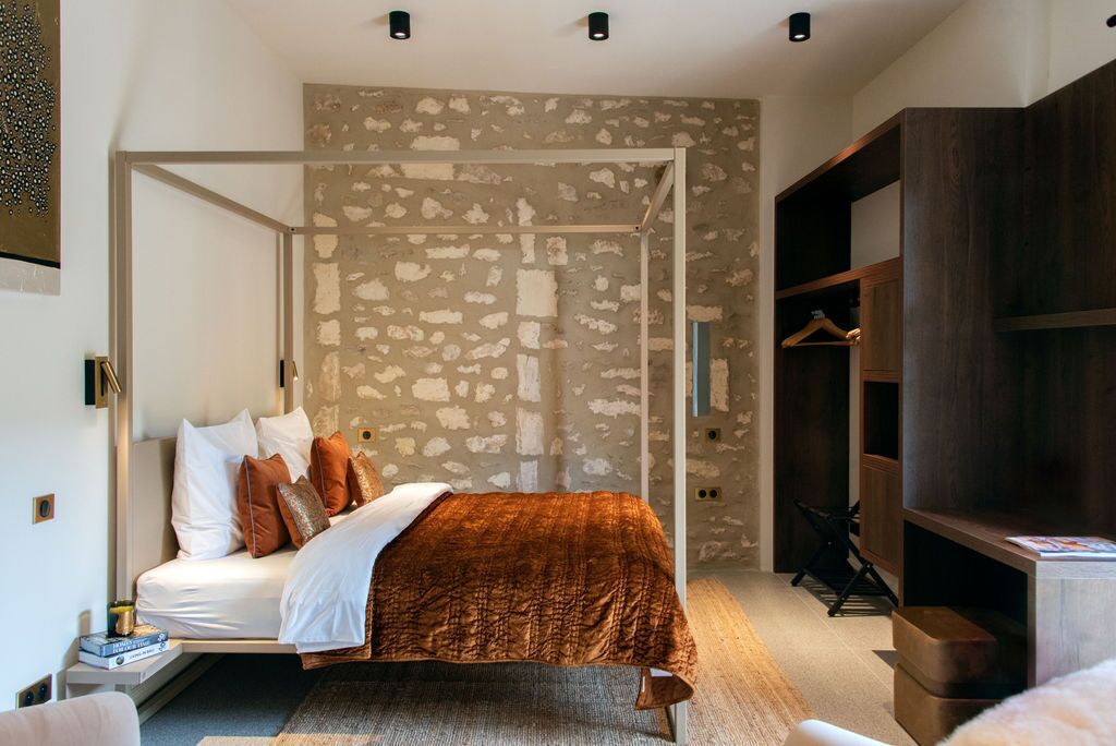 Un dormitorio moderno con cama con dosel, pared con estampado de piedra y estanterías empotradas de madera.