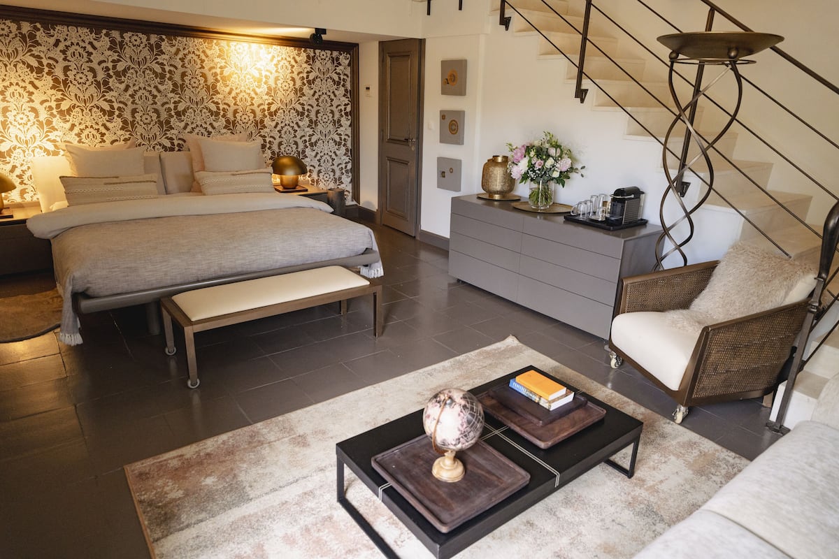 A modern bedroom with a large bed, bedside tables, a dresser, and a chair.