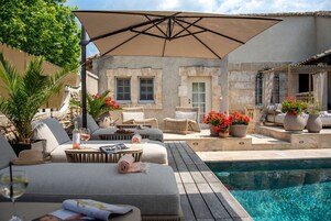 Una piscina al aire libre, sombrillas, sillones reclinables de piscina