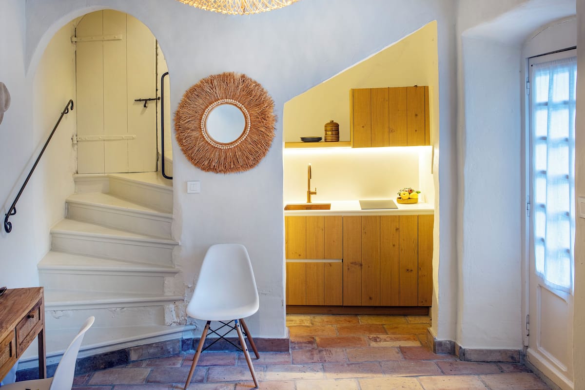 A staircase leading to a kitchen area with wooden cabinets and a hanging light fixture.