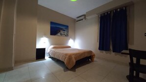 A bedroom with a bed, a nightstand, a chair, a painting on the wall, and a window with curtains. - Hotel Litoral (Buenos Aires)
