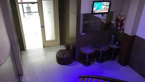 A hotel lobby with a reception desk, a television, and a seating area with stools. - Hotel Litoral (Buenos Aires)