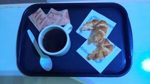 A tray with a cup of coffee, a croissant, and two packets of snacks. - Hotel Litoral (Buenos Aires)