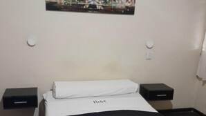 A hotel room with a bed, a nightstand, a wall-mounted picture of the Eiffel Tower, and a bedside table. - Hotel Litoral (Buenos Aires)