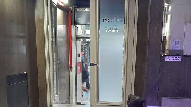 A lobby with a glass door, a purple cushioned seating area, and a tiled floor. - Hotel Litoral (Buenos Aires)