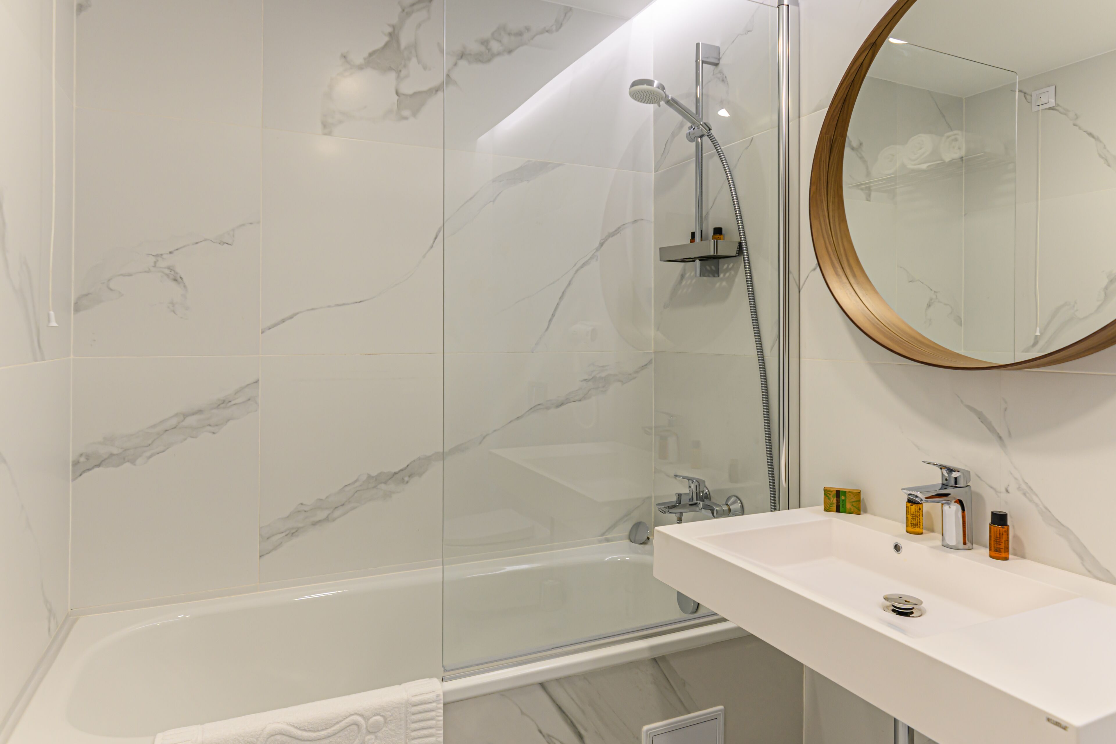 A modern bathroom with a bathtub, a shower, and a sink with toiletries.