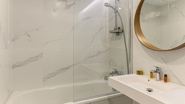 Un baño moderno con bañera, ducha y lavamanos con artículos de aseo.