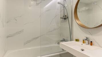 Une salle de bain moderne équipée d’une baignoire, d’une douche et d’un lavabo avec des articles de toilette.