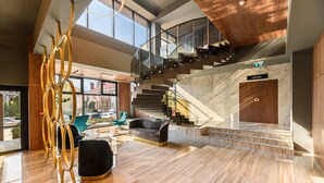A spacious lobby with a modern staircase, a seating area, and a view of the city. - Hotel Central Pascani (Pascani)