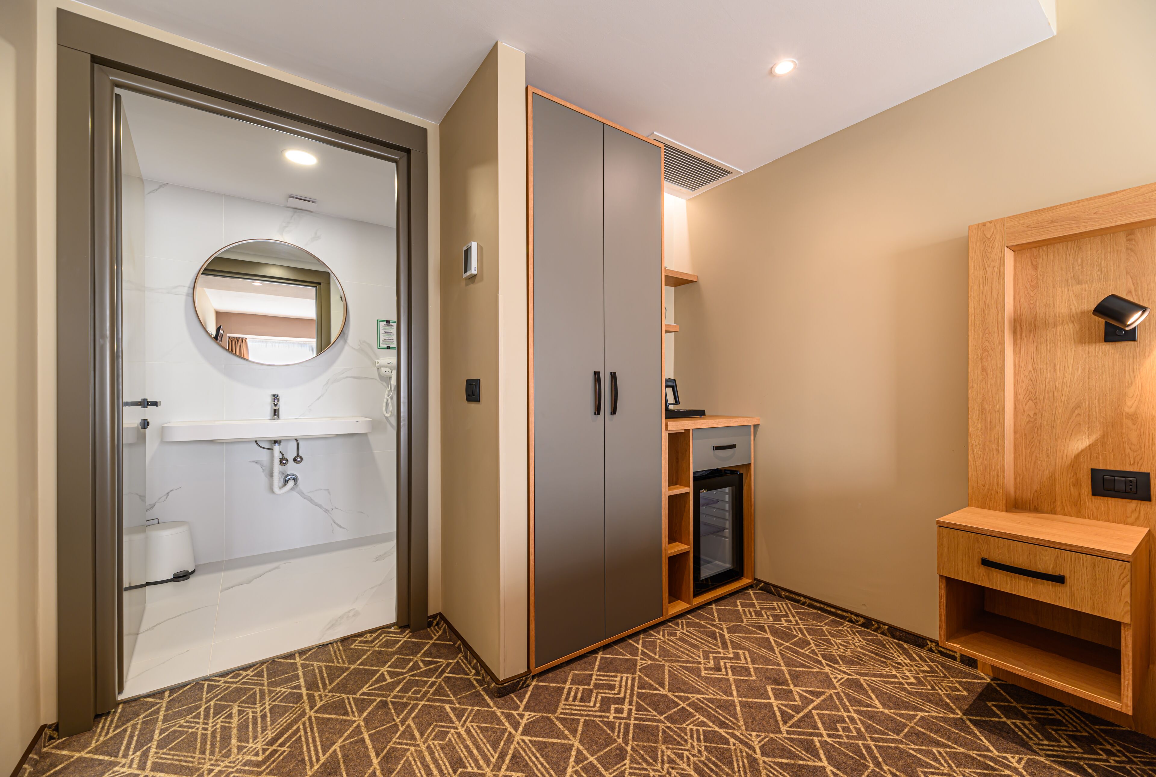 Quarto de hotel com banheiro, guarda-roupa e uma pequena mesa.