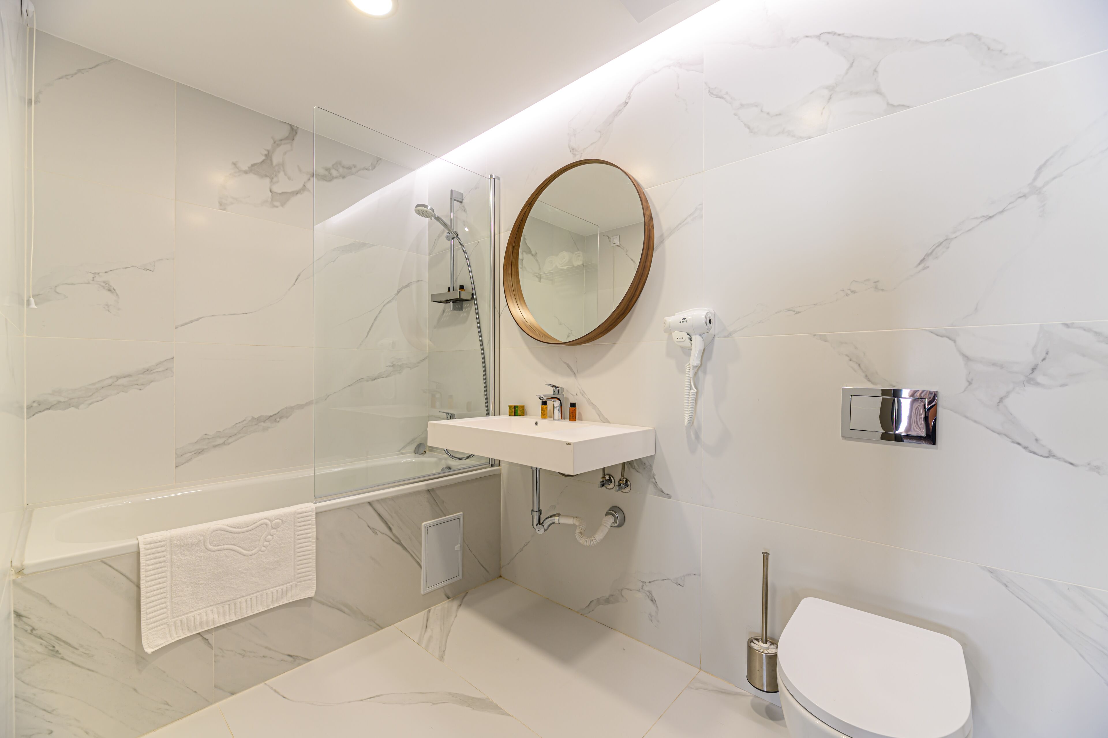 Une salle de bain moderne avec un sol en marbre, une baignoire sur pieds, un lavabo avec un miroir et des toilettes.