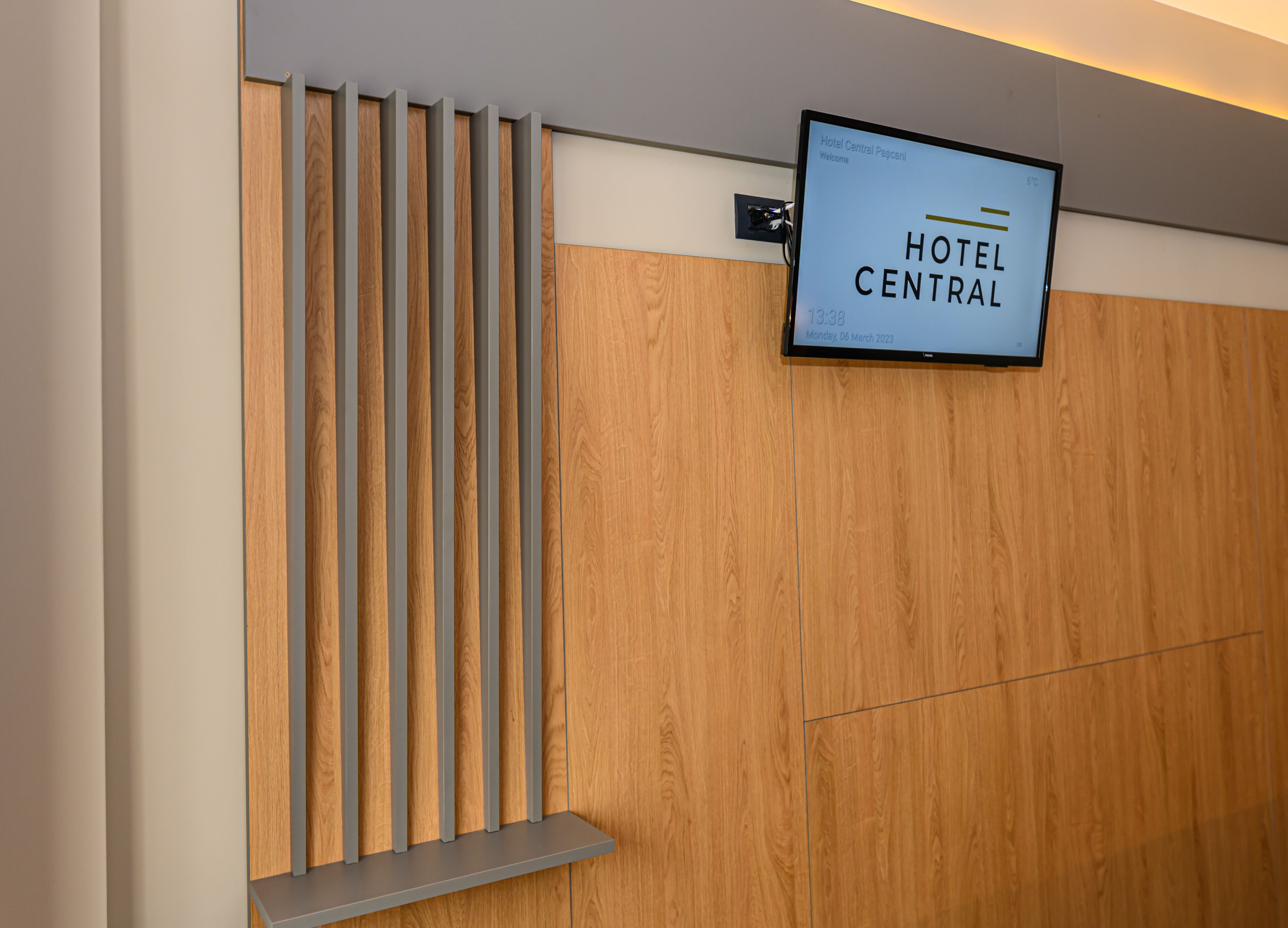 A reception area with a digital sign displaying "HOTEL CENTRAL" and a wooden panel design.