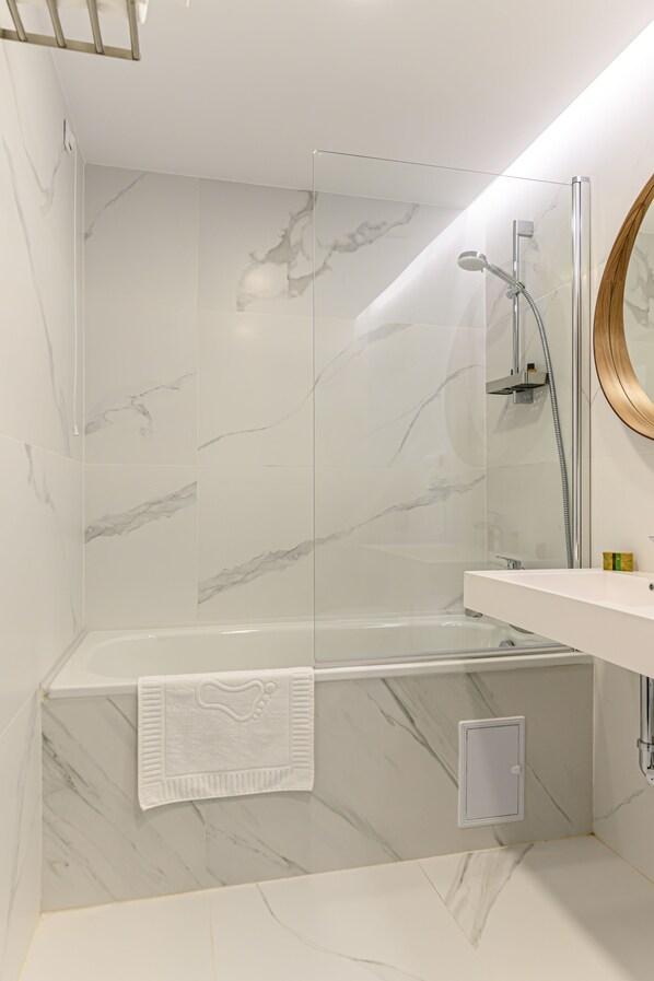 A modern bathroom with a glass-enclosed shower, a white bathtub, and a vanity with a mirror. - Hotel Central Pascani (Pascani)