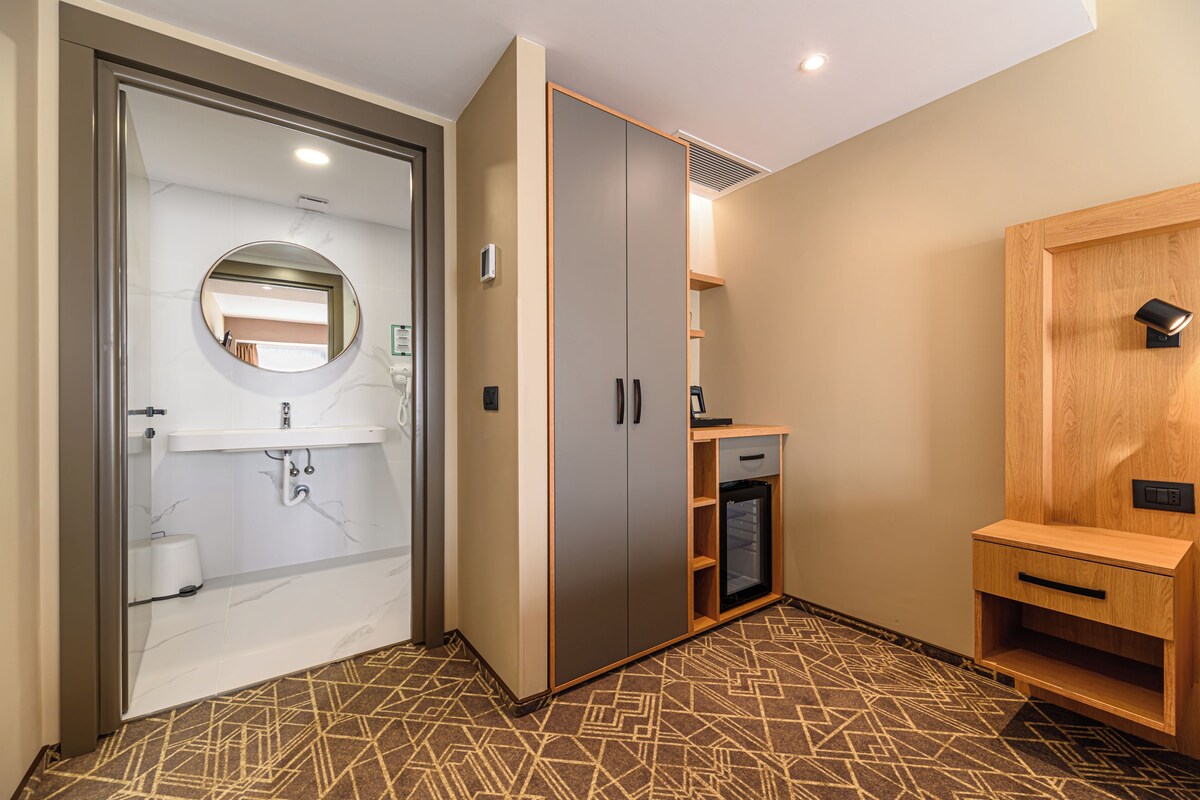 A hotel room with a bathroom, a wardrobe, and a small desk.