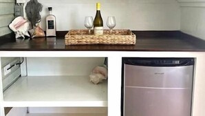 Una cocina moderna con un lavavajillas de acero inoxidable, una botella de vino y copas sobre una bandeja de mimbre.