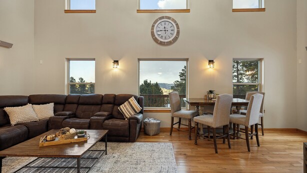 A spacious living room with a brown leather sofa, a wooden coffee table, and a dining area with a wooden table and chairs. - 3 King Beds * Game Room * Heated Garage * Trails (Lead)