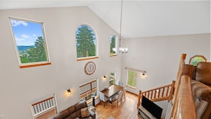 A spacious living area with a high ceiling, large windows, a dining table, and a cozy seating area. - 3 King Beds * Game Room * Heated Garage * Trails (Lead)