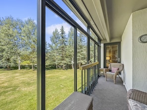 A balcony with a view of a grassy yard and trees, furnished with wicker chairs and a bench. - Wh102 Wheeler House 2 Bedroom Condo by RedAwning (Copper Mountain)