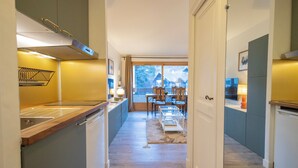 Una cucina moderna con un piano di lavoro in legno, forno integrato e vista su una zona pranzo con tavolo e sedie.