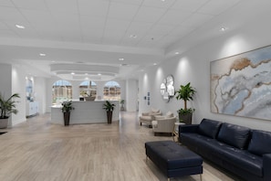 A spacious lobby with a reception desk, seating area, and large windows offering views of the outside.