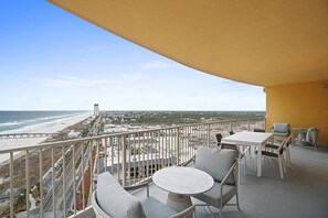 A balcony with a white table and chairs, overlooking a beach and cityscape. - 🏖️ADA Compliant Master-Great Gulf Views-Corine's Corner🏖️ (Panama City Beach)