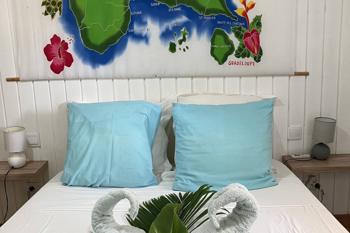 Un lit bien fait, avec des oreillers bleu clair et un arrangement floral sur une couvre-lit bleue.