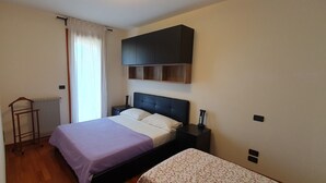 A bedroom with a bed, bedside table, and a built-in shelf above the bed.