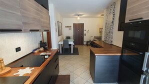 A modern kitchen with a central island, a dining area, and a refrigerator.