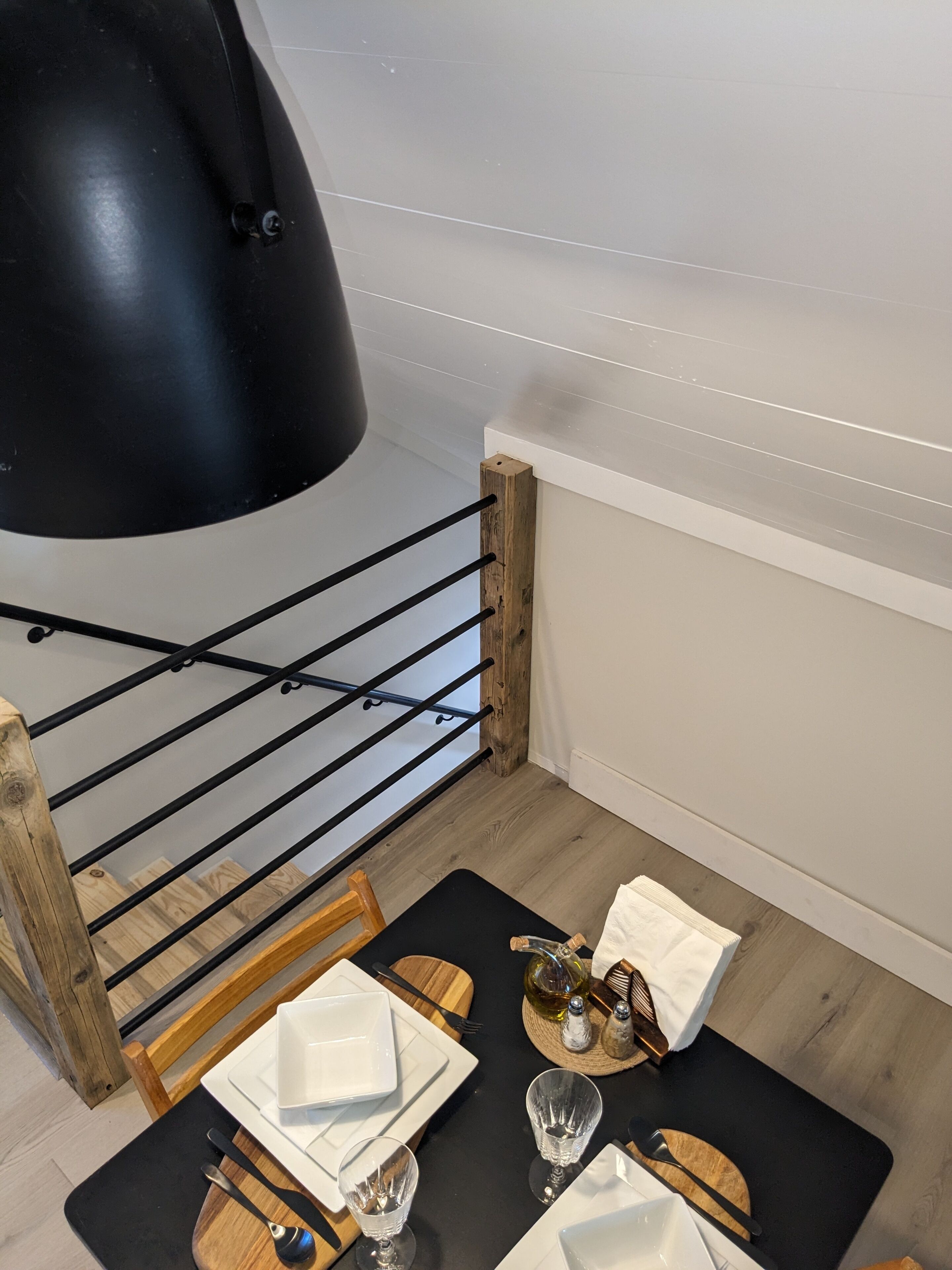 Ein Essbereich mit einem schwarzen Tisch, Holzstühlen und einer schwarzen Pendelleuchte.