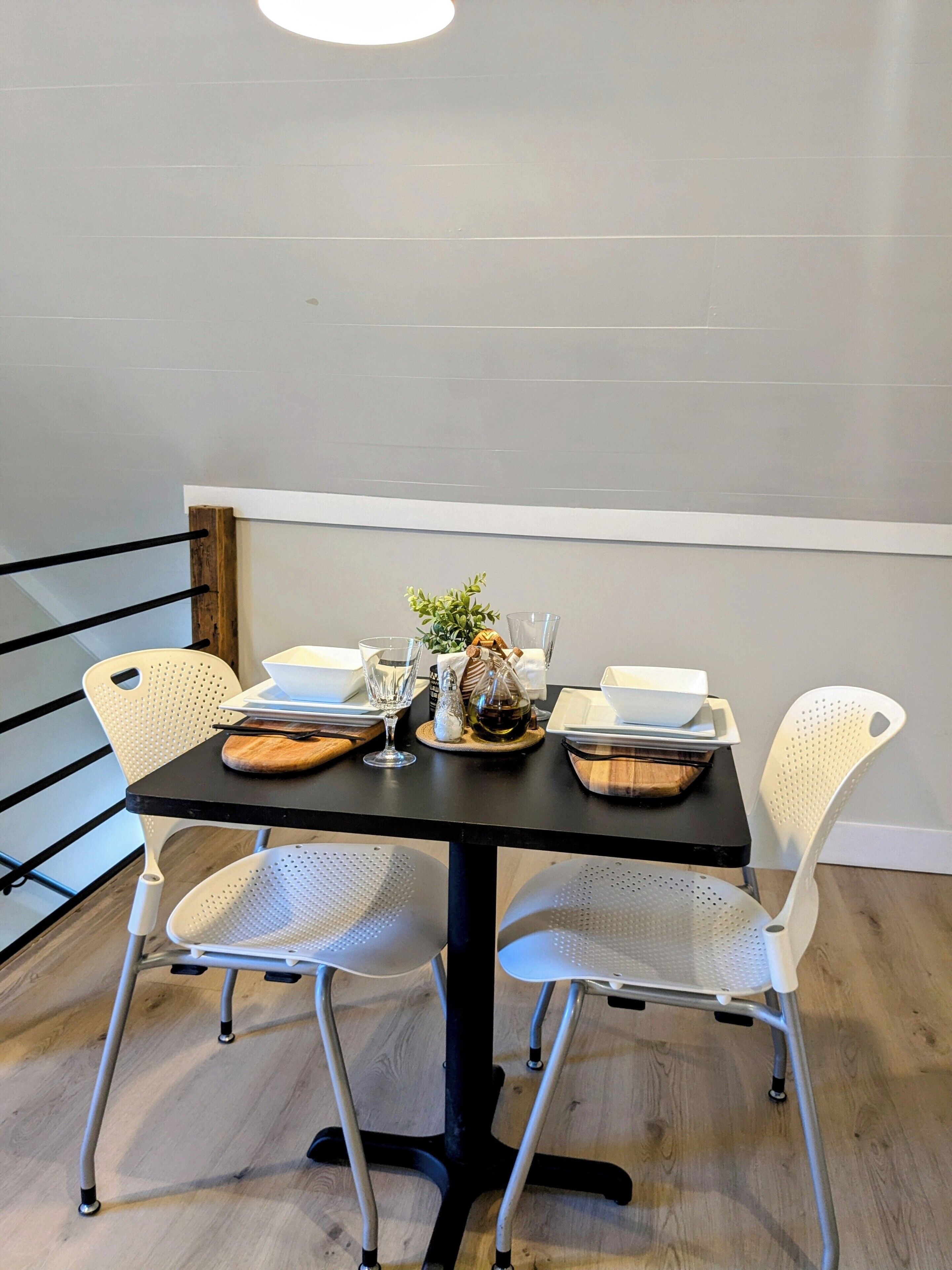 A dining area with a black table, white chairs, and a small plant centerpiece.