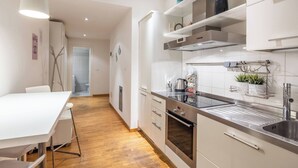 A modern kitchen with white cabinets, stainless steel appliances, and a wooden floor. - Maison Chanel (Bologna)