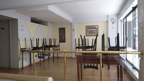 A spacious room with a wooden floor, a dining table with chairs, a glass railing, and a large window. - SUIPACHA INN HOTEL (Buenos Aires)
