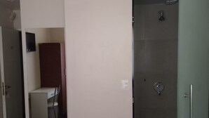 A hotel room with a bed, a shower, a desk with a chair, and a small kitchenette. - SUIPACHA INN HOTEL (Buenos Aires)
