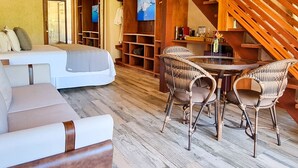 A spacious living area with a wooden staircase, a sofa set, wicker chairs, and a television. - Valle Paradiso (Imbituba)