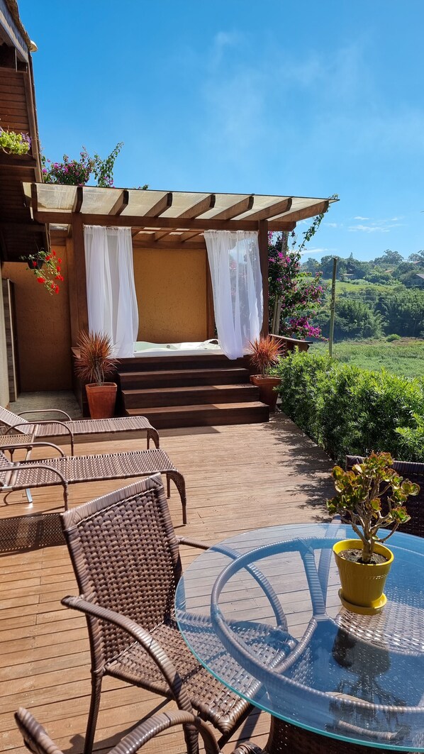 A patio with wicker chairs, a glass table, and a yellow potted plant. - Valle Paradiso (Imbituba)