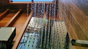 A room with a large window overlooking a scenic landscape, a wooden bench, and a metal rack. - Valle Paradiso (Imbituba)