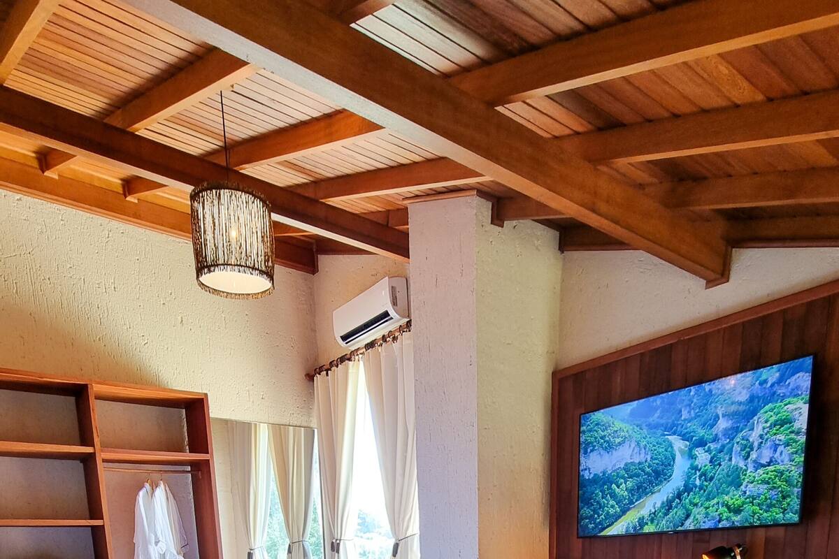 Ein gemütliches Zimmer mit zwei Betten, einem Fernseher und einer Holzbalkendecke.