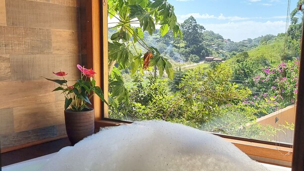 A bathtub with a view of a lush green landscape and mountains. - Valle Paradiso (Imbituba)