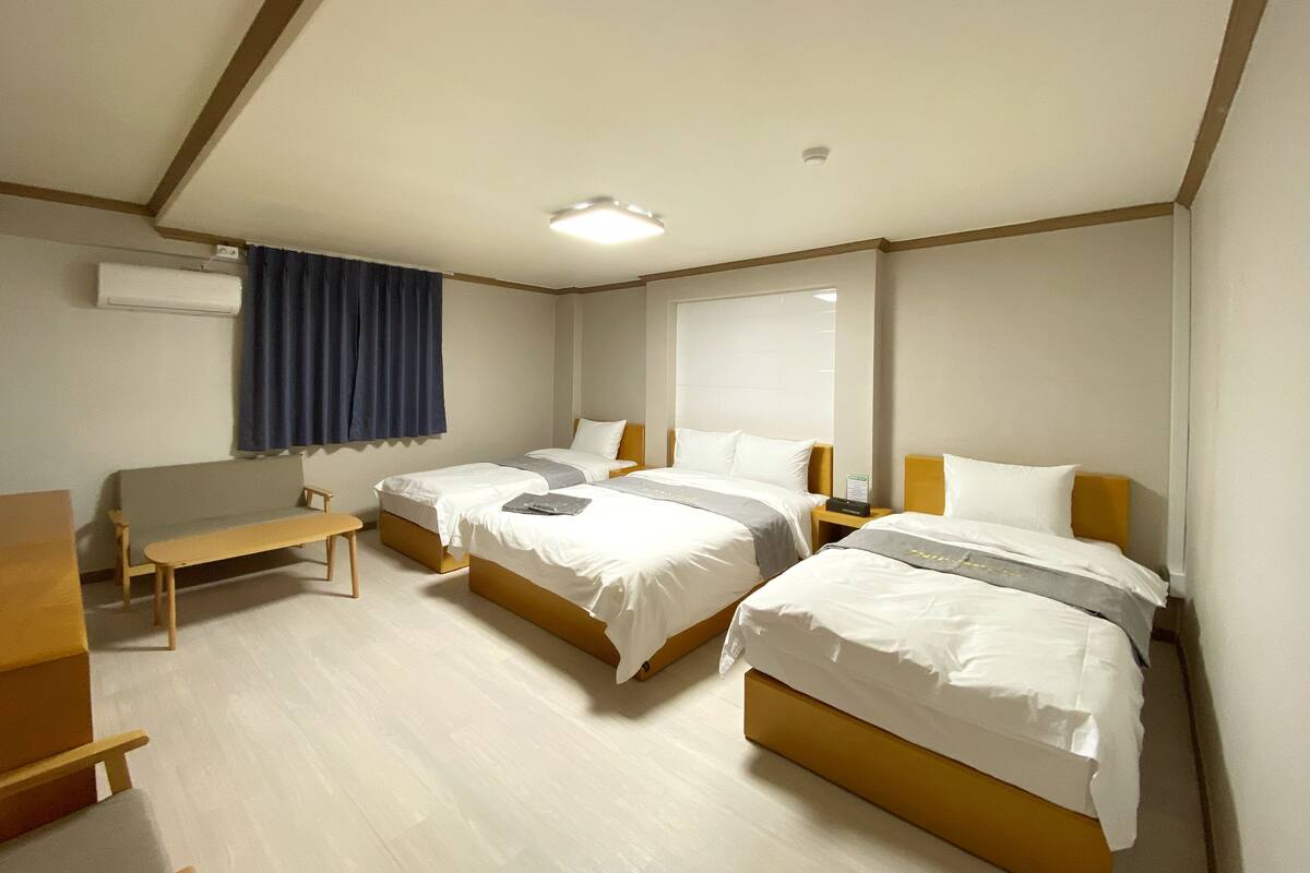 A hotel room with two beds, a desk, and a chair.