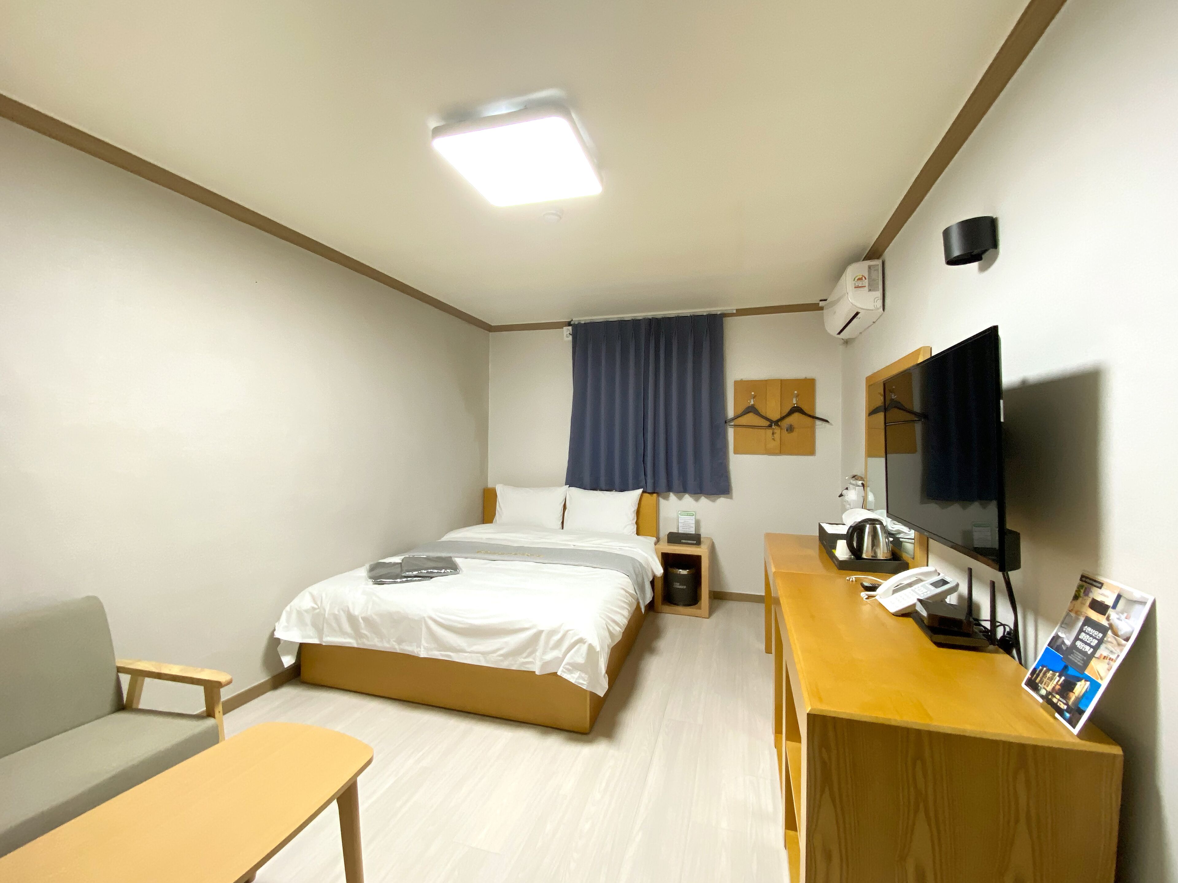 Une chambre d’hôtel avec un lit, un bureau, une chaise, une télévision et une fenêtre avec des rideaux.