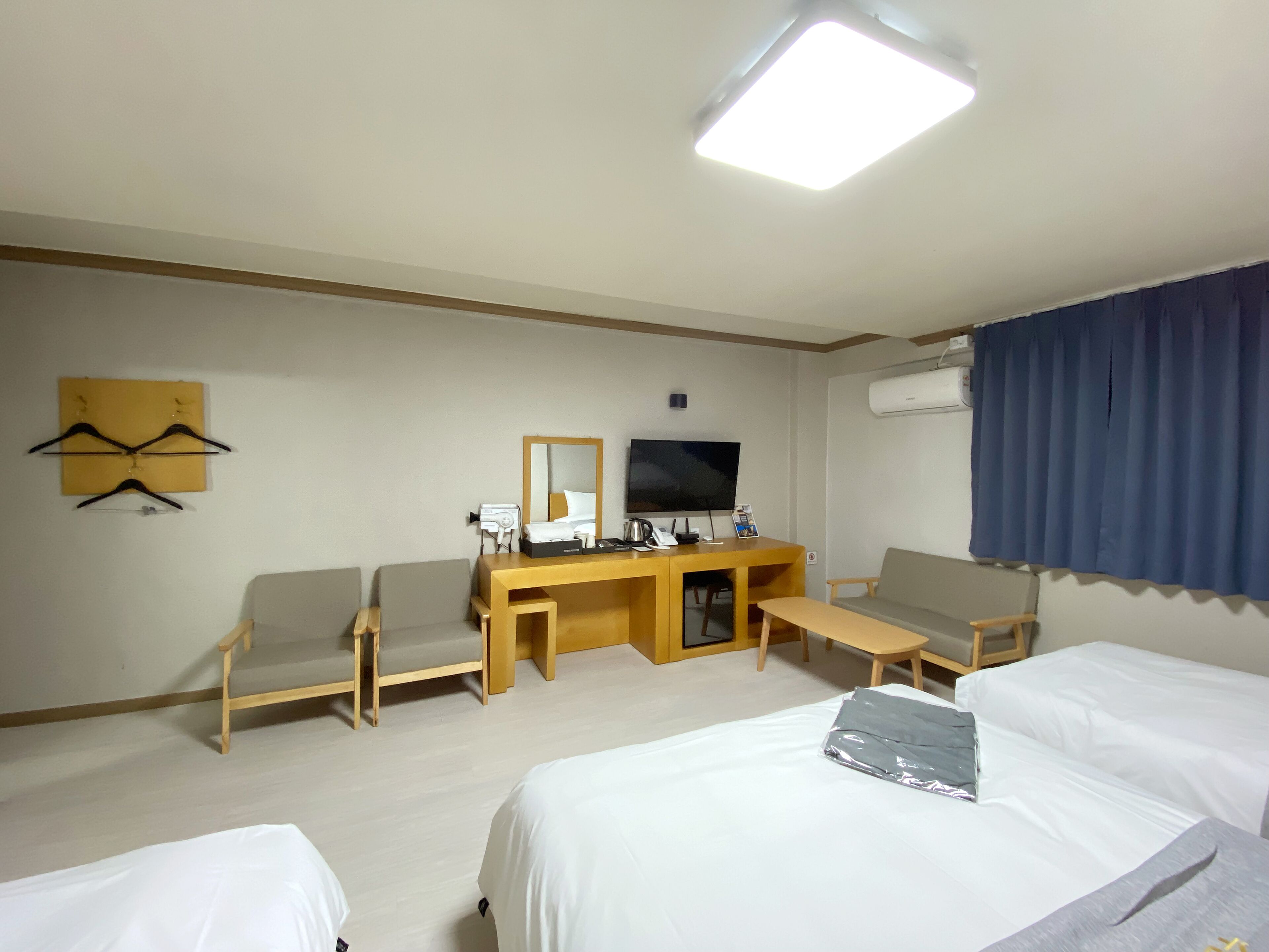 Habitación de hotel con cama, dos sillas, escritorio con televisor y espejo.