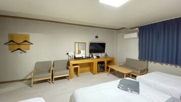 Habitación de hotel con cama, dos sillas, escritorio con televisor y espejo.
