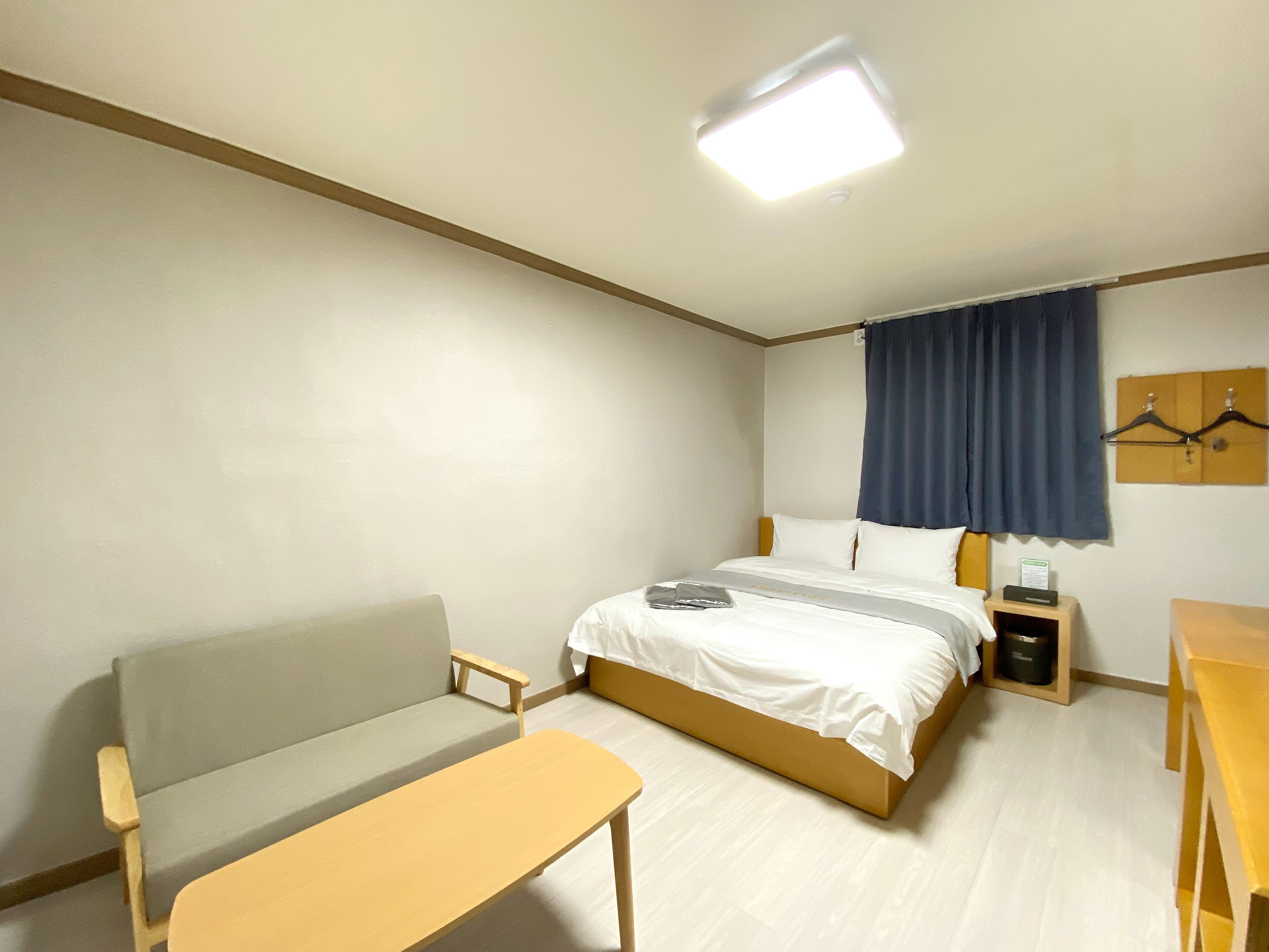 A hotel room with a bed, a small table, a sofa, and a desk.