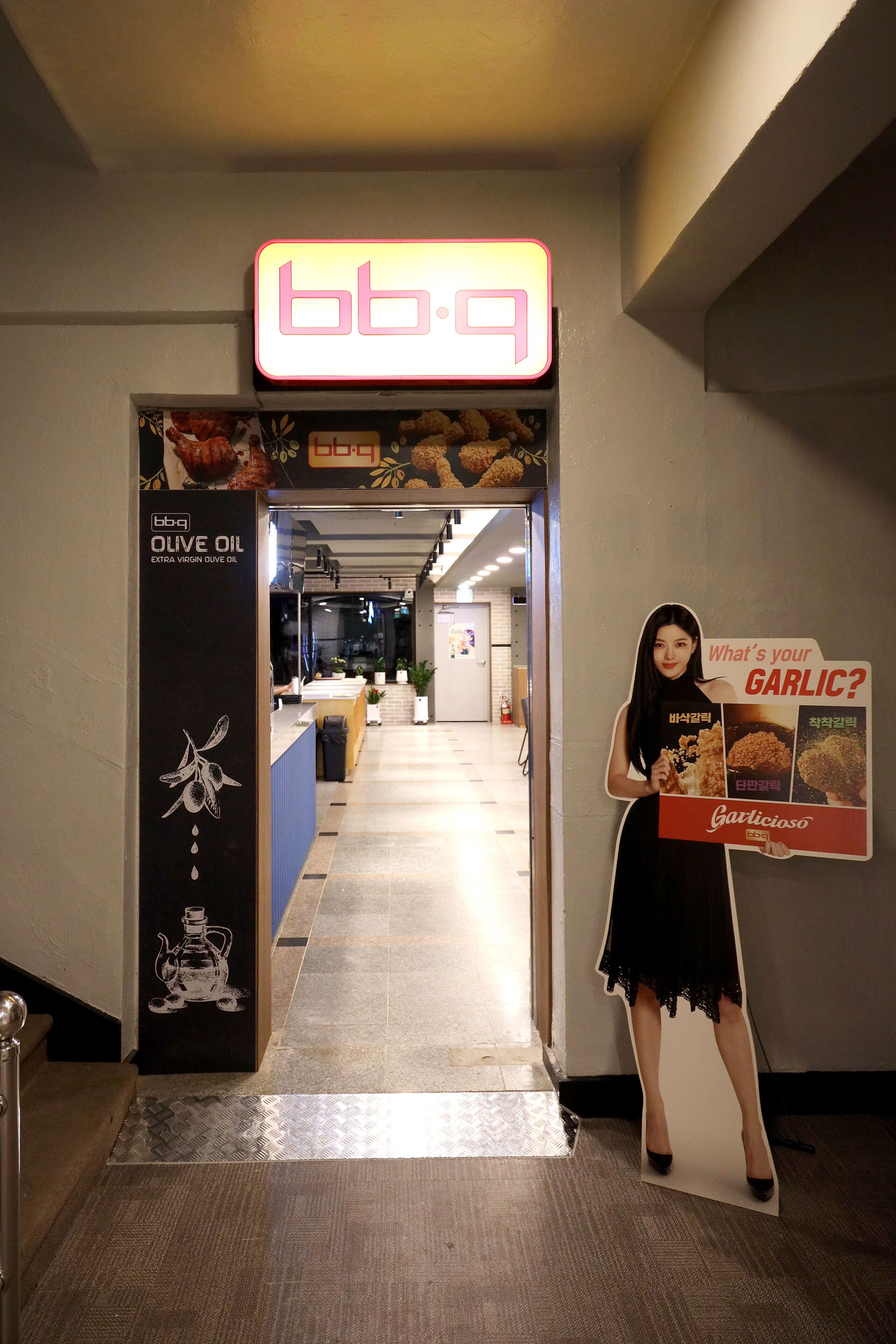 A hallway with a neon sign reading "bb-q" and a poster advertising garlic.